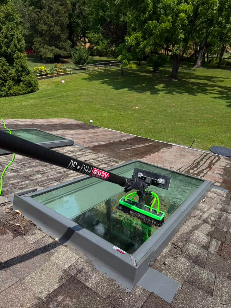 Skylight glass being scrubbed with a water fed pole on a Bucks County roof