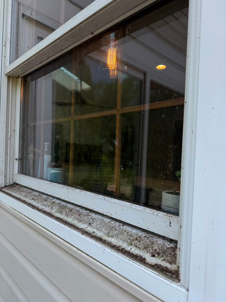 Window frame and sill packed with grit and debris before cleaning at a Bucks County home