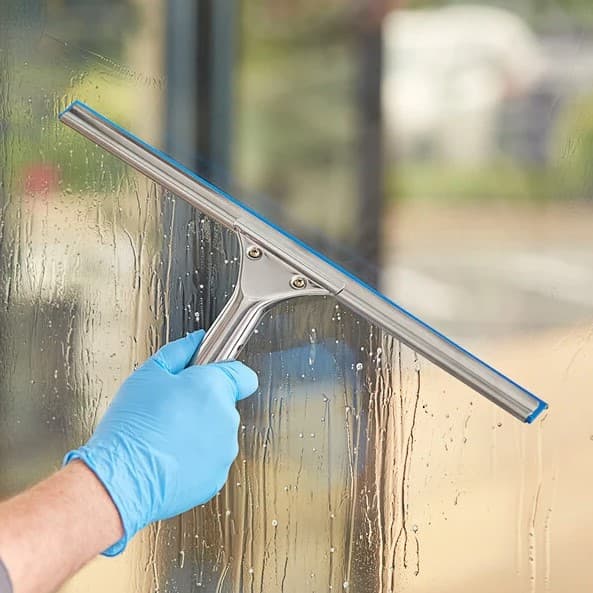 Squeegee pulling water down a pane of interior window glass in a Bucks County home
